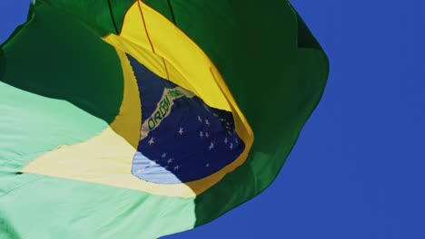 Die-Brasilianische-Flagge-Weht-In-Zeitlupe-Im-Wind-Mit-Einem-Blauen-Himmelshintergrund