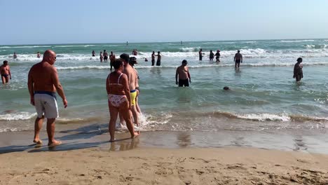 Gente-Caminando-Y-Bañándose-En-La-Orilla-Del-Mar-En-Verano-En-Vacaciones