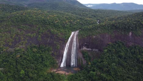 Frontal-aerial-shot-of-a-large-waterfall-located-in-the-middle-of-the-jungle