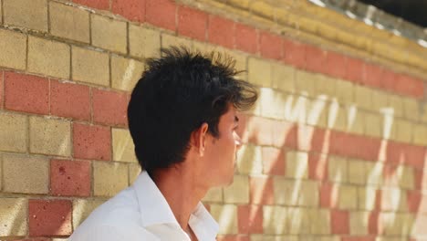 Asian-male-model-with-short-black-hair-and-white-shirt-posing-against-brick-wall