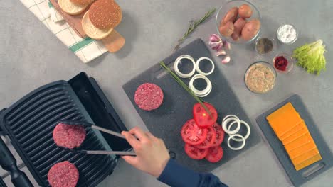 An-aerial-view-of-raw-burger-meat-which-is-being-placed-on-grilling-machine-by-the-chef