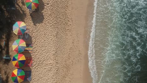 Aerial-view-of-the-beach,-flying-over-the-people-enjoying-sea-shore-with-waves-and-sunshine