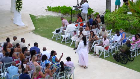 Female-pastor-officiant-walks-down-aisle-at-outdoor-wedding-in-tropical-resort-location