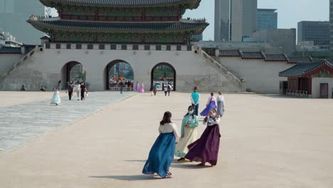 Young-girls-in-protective-face-masks-wearing-Hanboks-and-take-pictures-in-Gyeongbokgung-Palace-with-Gwanghwamun-gate-behind-in-summer