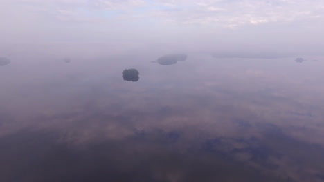 Asombrosas-Imágenes-De-Drones-De-Un-Gran-Lago-En-Finlandia-Con-Pequeñas-Islas-Al-Amanecer-Brumoso