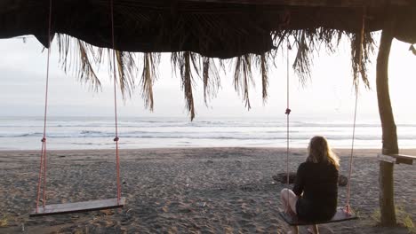 Junge-Blonde-Frau-Genießt-Einen-Wunderschönen-Sonnenuntergang,-Während-Sie-Auf-Einer-Schaukel-An-Einem-Strand-In-Costa-Rica-Sitzt