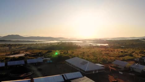 Dzaleka-Refugee-Camp-Settlement-on-Sunrise-Drone-Approach,-Golden-Hour