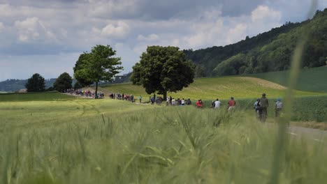 Wide-shot-showing-crowd-of-cyclist-on-road-between-rural-fields-and-hills-in-Switzerland---Climate-Friendly-Slowup-Event