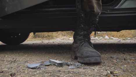 Soldier-stepping-out-of-the-car,-stepping-on-broken-glass-with-military-boots