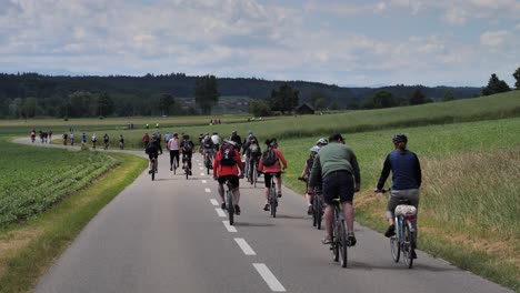 Rear-view-pov-of-crowd-of-cyclist-riding-bike-on-asphalt-road-in-switzerland-during-car-free-event