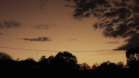 Australischer-Sonnenuntergang-Mit-Großer-Roter-Altocumulus-Wolkenbildung-Und-Gummibäumen-Im-Zeitraffer,-Maffra,-Victoria,-Australien