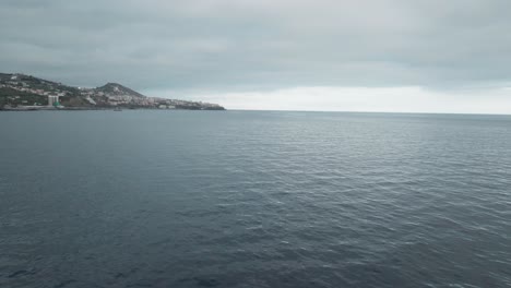 Catamaran-Boat-Sailing-On-The-Atlantic-Ocean-Towards-City-Of-Funchal-In-Madeira,-Portugal-On-A-Cloudy-Day