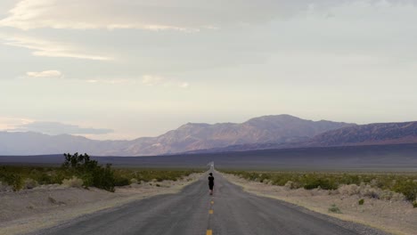Woman-walking-in-the-middle-of-the-road-in-Death-Valley-National-Park-in-California,-USA