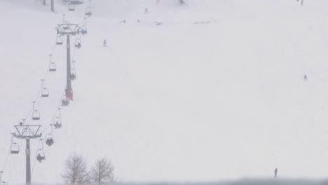 Zeitrafferaufnahme-Eines-Sessellifts-Und-Von-Skifahrern,-Die-Einen-Hügel-Hinunterfahren