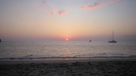 Wide-shot-of-sun-setting-in-the-horizon-at-Asian-beach---ultra-slow-motion