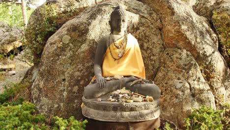 Buddha-statue-with-small-offerings-around-it-at-the-stupa-in-Red-Feather-Lakes,-CO