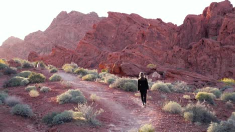 Slow-motion-shot-of-female-hiker-at-sunset-in-Valley-of-Fire-State-Park,-Nevada,-USA