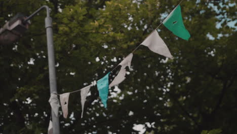 Slow-motion-shot-of-flags-blowing-in-the-wind-behind-a-tree-on-a-street-in-Belfast,-Northern-Ireland