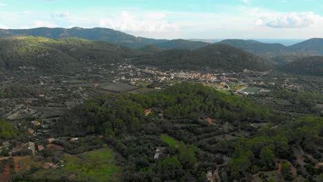 Drone-footage-over-a-vally-mooving-towards-a-small-town-with-mountains-in-the-background