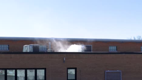 Eine-Große-Industrielle-Klimaanlage-Auf-Dem-Flachdach-Eines-Geschäftsgebäudes-Stößt-Weißen-Rauch-Aus,-Der-Darauf-Hinweist,-Wie-Eiskalt-Die-Außentemperaturen-Sind