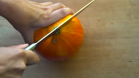 Top-down-view-of-male-hands-struggling-to-cut-a-Hokkaido-pumpkin-in-half