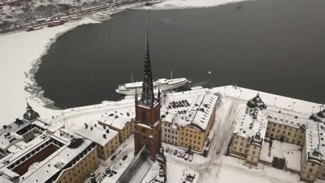 Wide-aerial-shot-of-Stockholm-city-scene-with-panoramic-view-of-Riddarfjärden-while-zooming-in-on-famous-church-of-Riddarholm