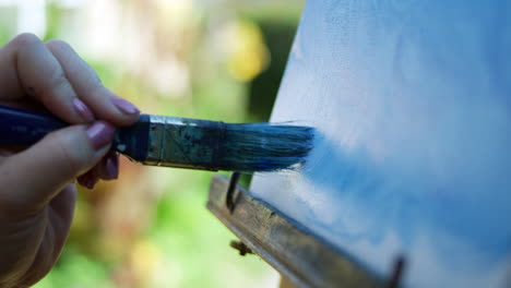 SLOW-MOTION-CLOSE-UP-video-of-female-artist-applying-blue-paint-in-a-downward-motion-onto-canvas