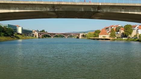 Dlying-a-drone-under-the-bridge-across-river-Drava-in-Maribor,-Slovenia