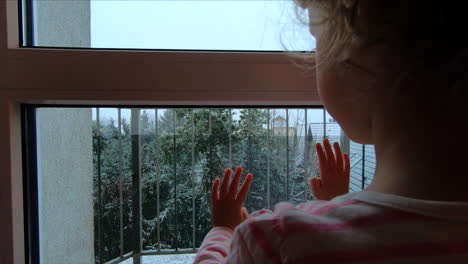 Ein-Kleines-Mädchen-Beobachtet-Durch-Das-Fenster-Den-Fallenden-Schnee