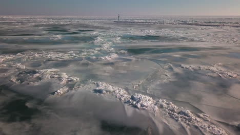 Ein-Leuchtturm-Am-Ende-Eines-Piers-Mitten-Im-Gefrorenen,-Eisigen-Eriesee-Im-Winter