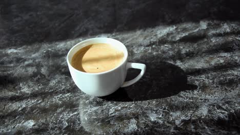 Weiße-Tasse-Mit-Kaffee-Auf-Einem-Schwarz-weiß-Gesprenkelten-Tisch