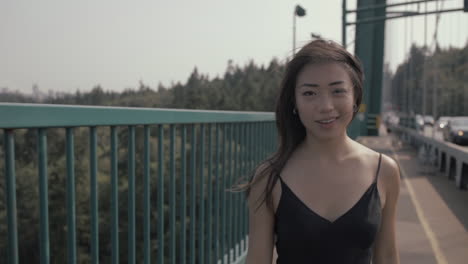 Medium-shot-of-Beautiful-smiling-asian-woman-walking-on-Lions-Gate-bridge-in-Vancouver,-Slowmo