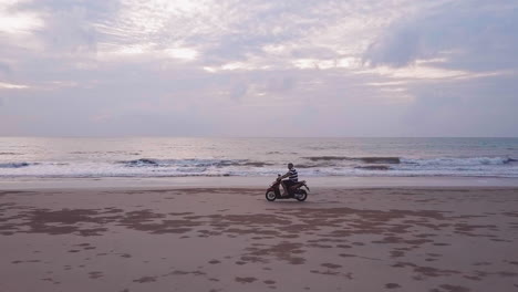 Drone-view-of-a-motorcycle-going-fast-on-the-beach-at-sunset