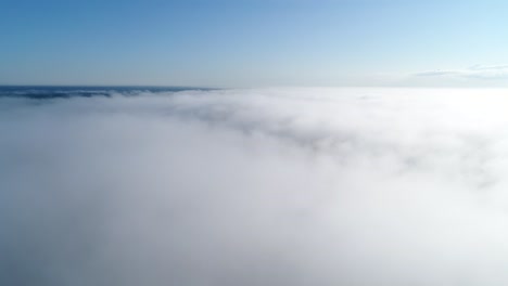 Vuelo-Sobre-Nubes-Brumosas-A-La-Luz-Del-Sol-De-La-Mañana-Con-Poca-Gloria-Y-Paisaje-Urbano-Bajo-Las-Nubes