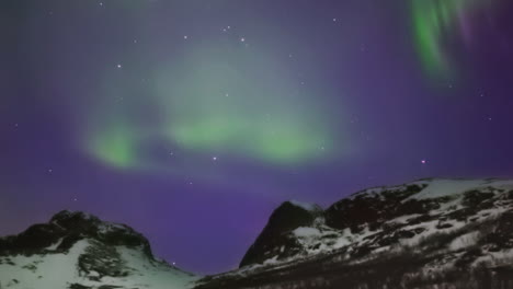 Bright-aurora-borealis-dancing-over-a-mountain-pass,-SLOW-PAN-LEFT-TO-RIGHT
