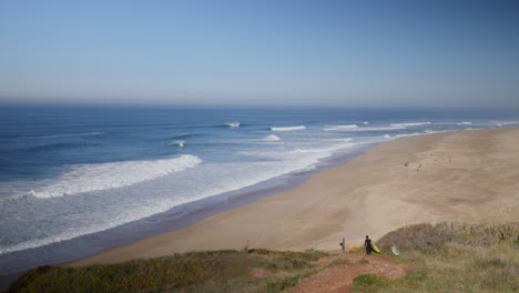 Surfer-heading-down-the-cliff-in-Praia-do-Norte,-Nazare