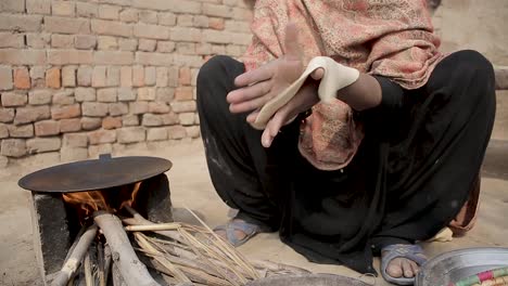 A-lady-prepares-Pakistani-roti-bread---then-places-it-on-a-fire-stove---pan