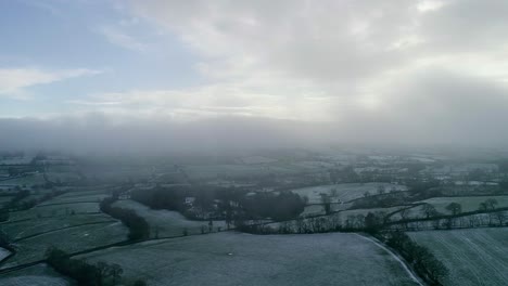 Mystic-aerial-shot-tracking-low-in-the-clouds-and-mist-above-a-frosty-english-countryside-setting