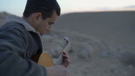 Musician-strumming-the-guitar-during-a-desert-sunset