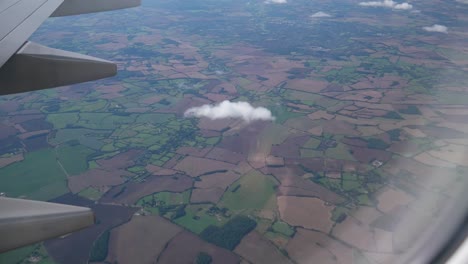 Vista-Desde-Un-Avión-De-Tierras-De-Cultivo-Que-Pasan-Con-Nubes-Pequeñas
