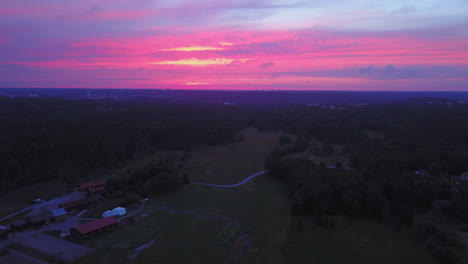 Aerial-drone-view-backwards,-above-the-countryside,-purple-sky,-at-a-colorful-sunset-or-dusk,-at-Albysjon,-Tyreso,-Sweden