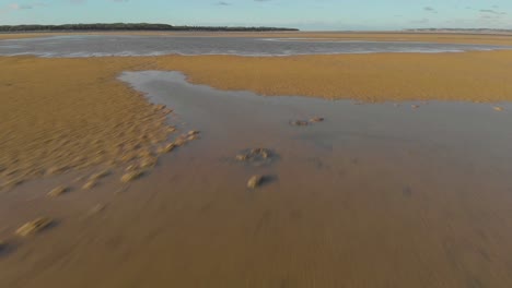 A-fast-low-flying-aerial-shot-of-the-sand-and-water-at-an-inlet-in-Victoria-Australia