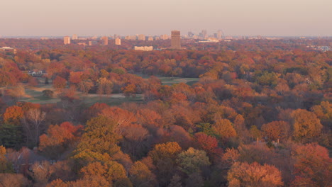 aerial-flyover-autumn-trees-and-city-skyline-tilts-down-to-reveal-suburban-house