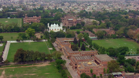 White-mosque-and-other-old-heritage-buildings-aerial-view-with-green-trees-and-city,-old-govt-official-buildings,-Beautiful-parks-and-play-grounds,-children-playing