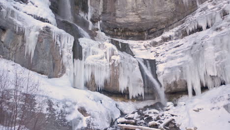 Wunderschöner-Wasserfall-Im-Winter-Mit-Eiszapfen-Links-Und-Rechts,-Die-Eine-Atemberaubende-Gefrorene-Szene-Schaffen-–-Dolly-Rein