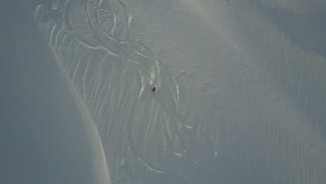 Drohne-Verfolgt-Backcountry-Skifahrerin,-Die-Den-Tiefschneehang-Hinunterfährt