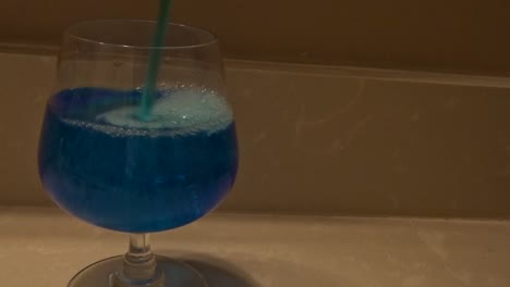 Frontal-shot-of-blue-liquid-being-poured-into-wine-glass