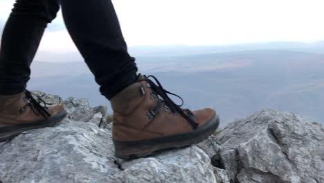 Woman-standing-on-a-rock,-wearing-mountain-footwear-and-black-jeans