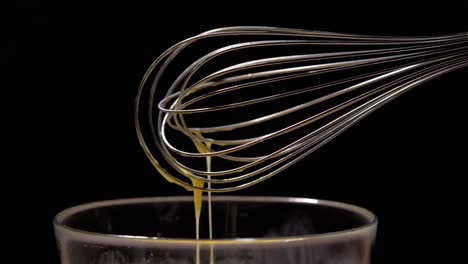Medium-shot-of-a-whisk-with-dropping-beaten-eggs-in-slow-motion
