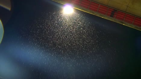 Footage-of-rain-drops-falling-from-the-top-in-slow-motion-down-the-bridge-with-a-light-in-the-night